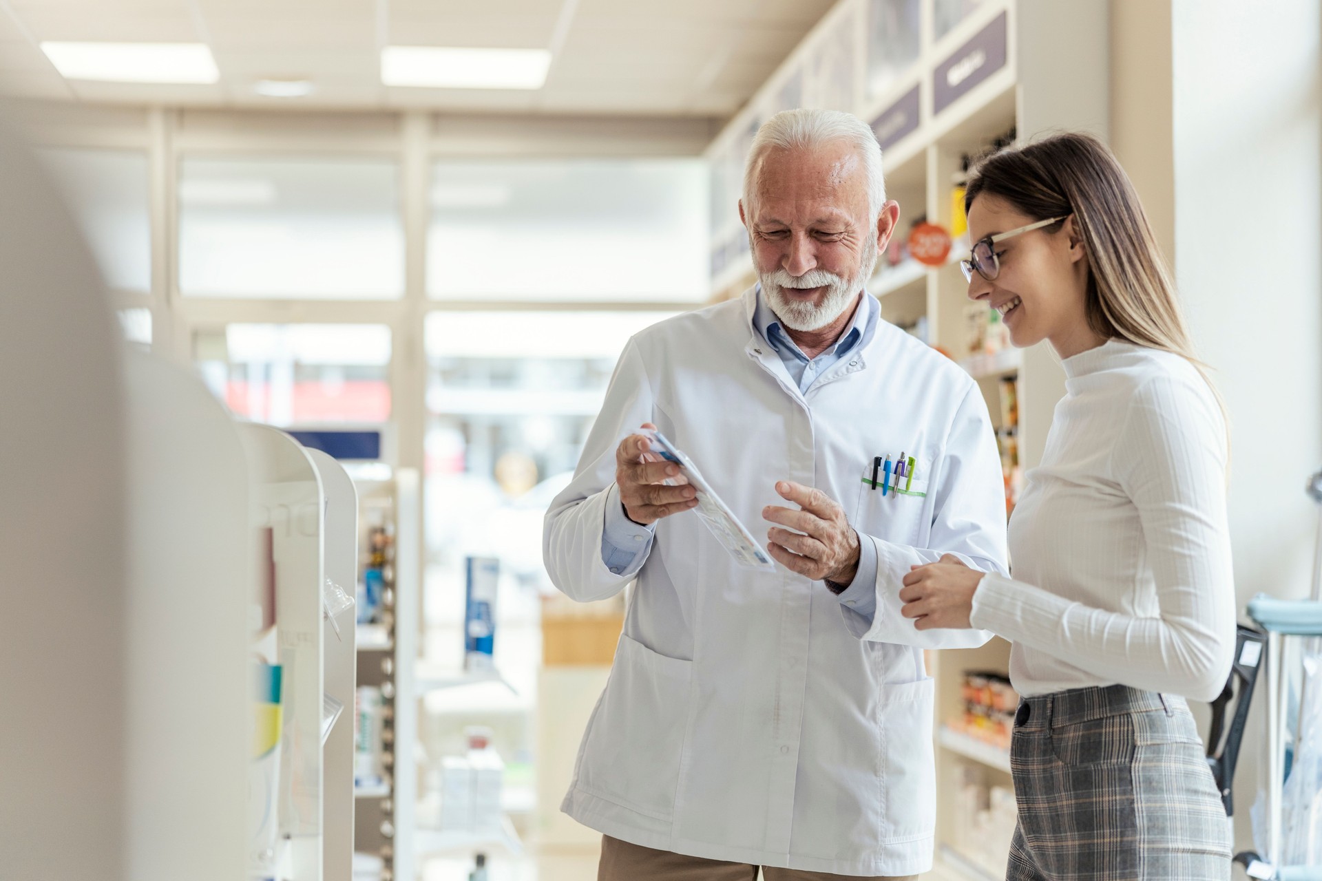 Consultation with a professional, conversation between the pharmacist and the client. A mature man explains drug therapy to a client. An experienced pharmacist recommends therapy to the client