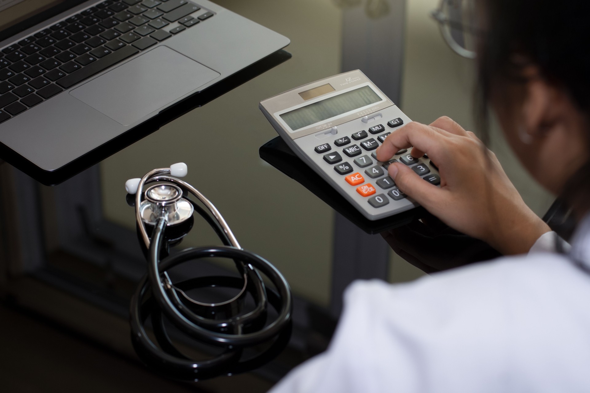 Female doctor with stethoscope using calculator